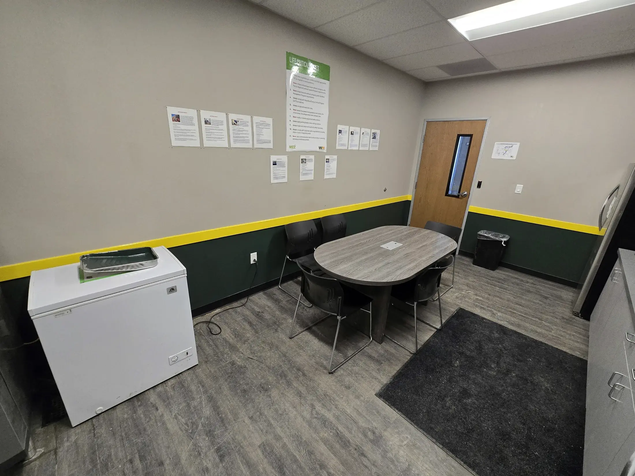 Commercial break room with gray walls, dark green lower wall color and bright yellow accent band