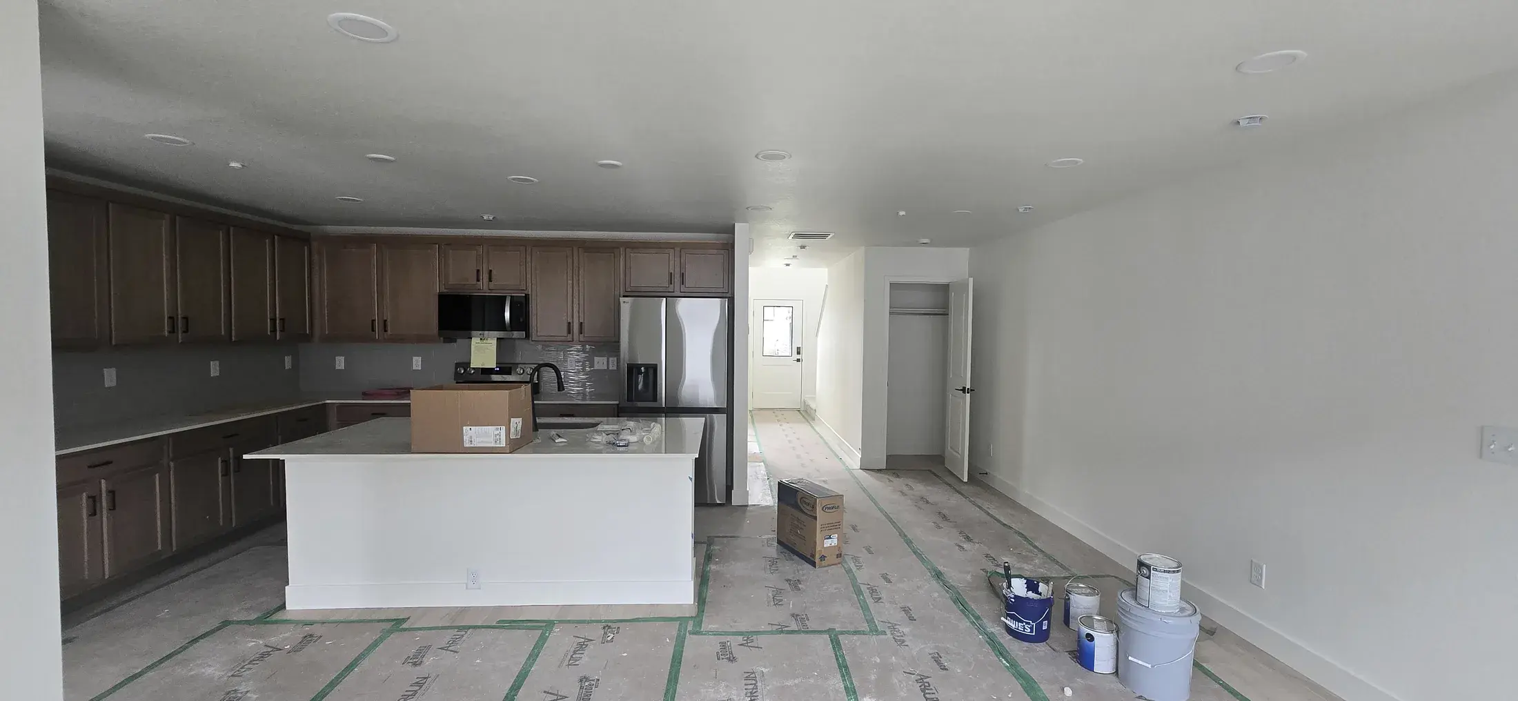 Open kitchen and living area during final interior painting and protection work