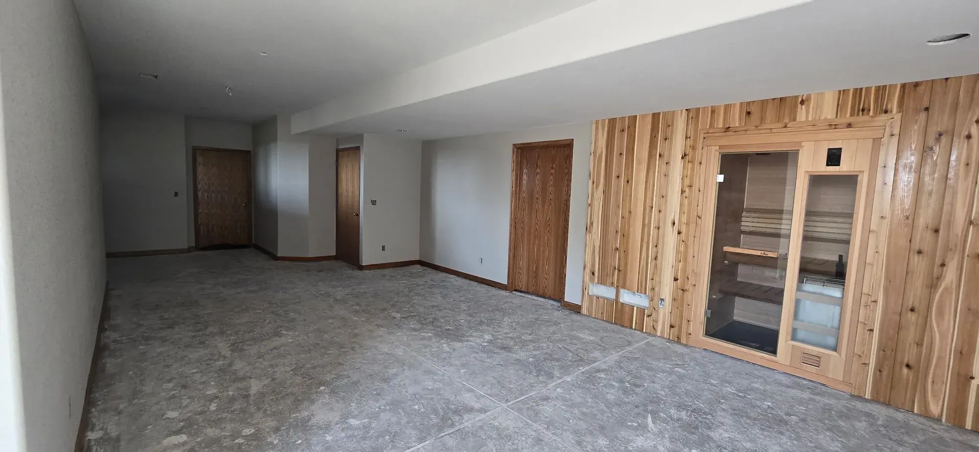 Finished lower-level interior with gray walls and natural wood sauna surround
